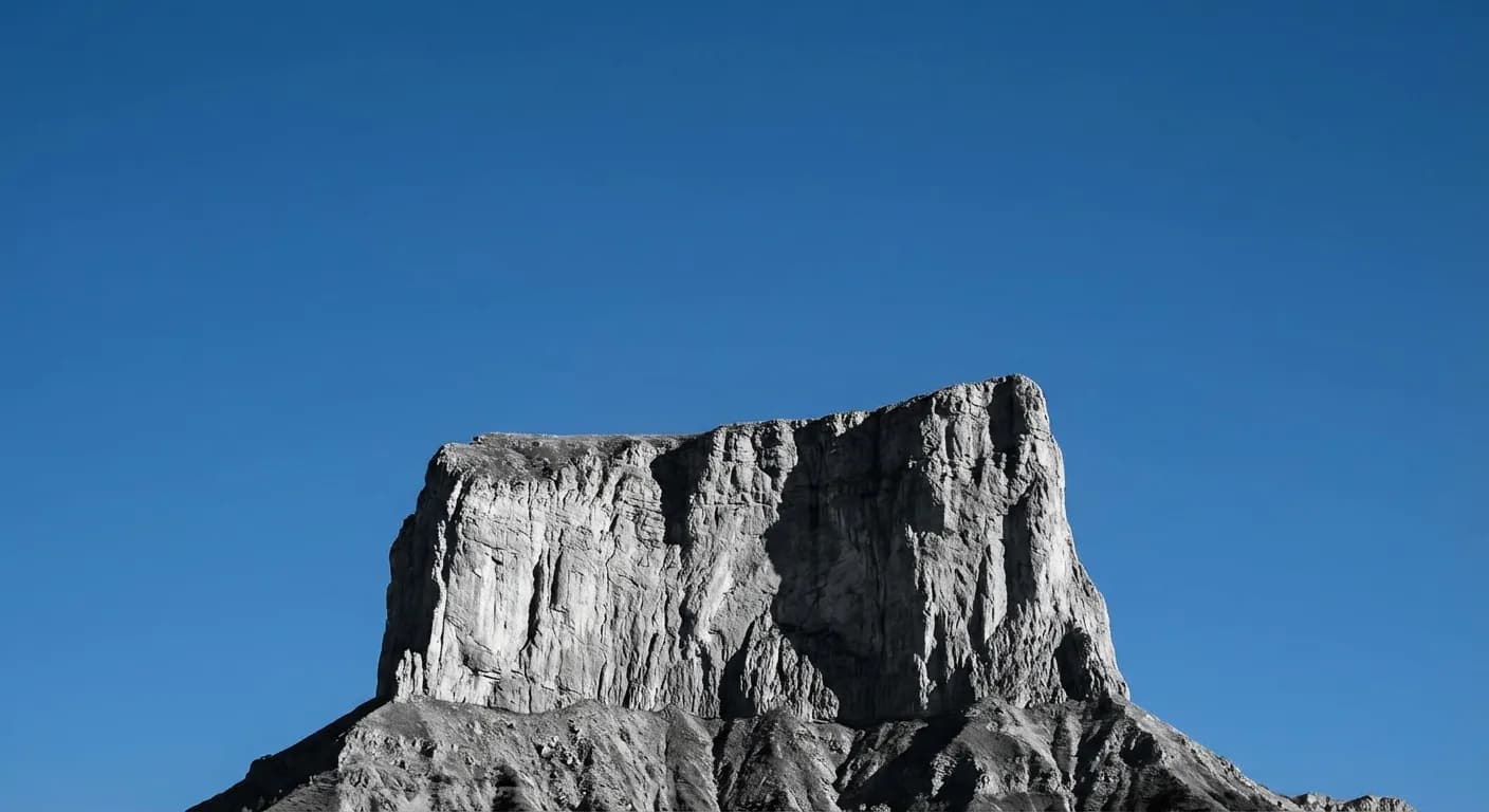 Mont Aiguille voie normale : Guide complet de l'ascension Silhouette minimaliste du Mont Aiguille sur fond de ciel bleu